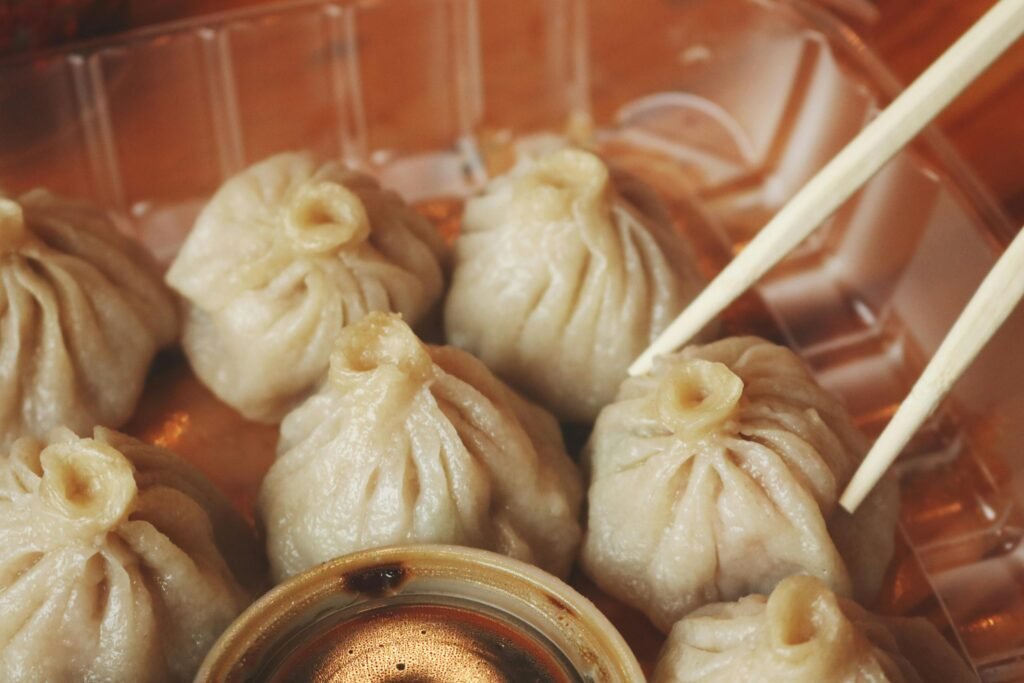 Close-up of delicious steamed dumplings with chopsticks and dipping sauce.
